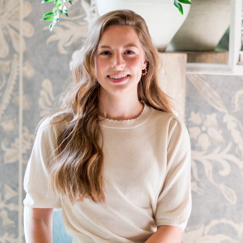 Amelia Paige smiling in front of a patterned wallpaper
